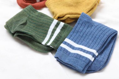 Beyaz battaniyede farklı yumuşak çoraplar, yakın çekim.