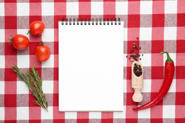 Boş tarif kitabı, biberli kepçe ve kareli masa örtüsü üzerindeki ürünler, düz yatak.
