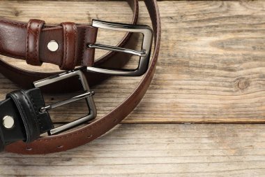 Ahşap masanın üzerinde iki deri kemer, manzaranın üstünde. Metin için boşluk