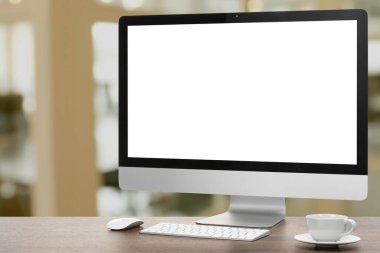 Boş ekranlı bilgisayar monitörü ve bulanık arka planda tahta masanın üzerinde fincan. Tasarım için model