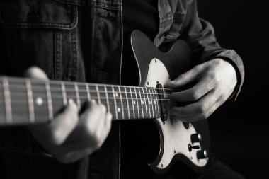 Karanlıkta gitar çalan adam, yakın plan. Siyah ve beyaz etkisi