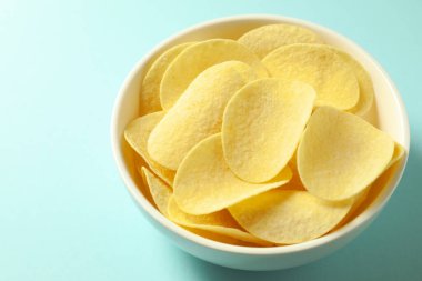 Açık mavi arka planda, kasede patates cipsi, yakın plan.