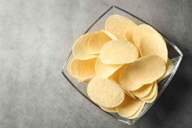 Gri masada leziz patates cipsleri, üst manzara. Metin için boşluk