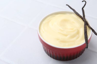 Lezzetli vanilyalı puding ve kapsüller beyaz fayanslı masada, yakın plan. Metin için boşluk