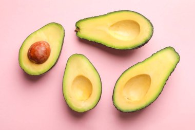 Halves of fresh avocados on pink background, flat lay