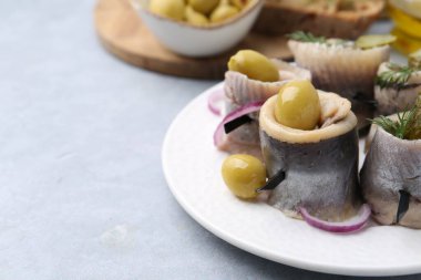 Gri masada zeytinli, turşulu, dereotlu ve soğanlı lezzetli ringa dürümleri, yakın plan. Metin için boşluk