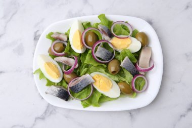 Ringa balıklı nefis salata, yumurta ve sebzeler beyaz mermer masada, üst manzara