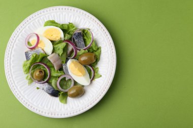 Ringa balıklı lezzetli salata, yeşil arka planda yumurta ve sebzeler, üst manzara. Metin için boşluk