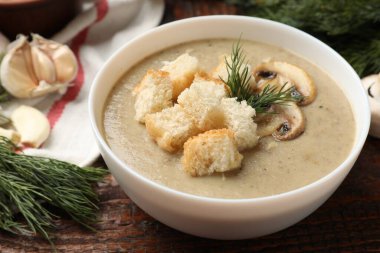 Lezzetli mantar kremalı çorba, kızarmış ekmek, dereotu ve ahşap masa malzemeleri, yakın plan.