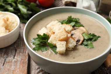 Lezzetli mantar kremalı çorba ve ahşap masada malzemeler, yakın plan.