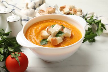 Beyaz mermer masa üzerinde maydanozlu ve domatesli balkabağı kremalı çorba, yakın plan.