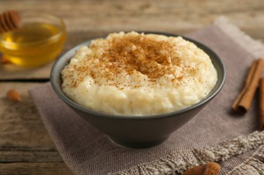 Tarçınlı lezzetli sütlaç, bal ve badem ahşap masada, yakın plan.