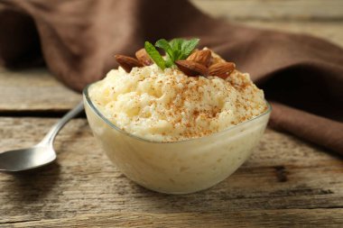 Tarçınlı lezzetli sütlaç, badem ve nane, ahşap masada servis edilir, yakın plan.