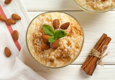 Tarçınlı lezzetli sütlaç, badem ve nane şekerli beyaz ahşap masa, düz uzanmış