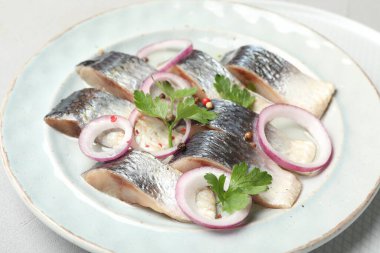 Beyaz masada baharatlı ve soğanlı lezzetli ringa balıkları, yakın plan.