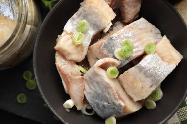 Siyah masada yeşil soğanlı lezzetli ringa balıkları, yakın plan.