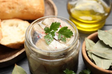 Kavanozda baharat ve siyah masada ekmek olan lezzetli ringa balıkları.