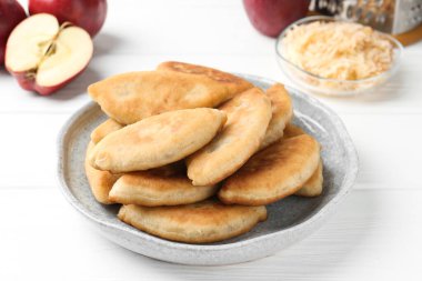 Lezzetli kızarmış pirinçler (doldurulmuş turtalar) ve beyaz ahşap masada elmalar, yakın plan.