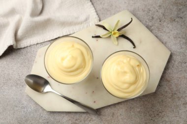 Lezzetli vanilyalı puding, kapsüller ve çiçek gri masada, düz uzanmış