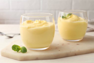 Beyaz ahşap masada naneli vanilyalı puding.