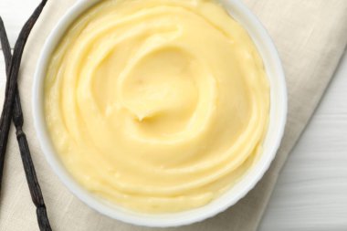 Lezzetli vanilyalı puding ve beyaz ahşap masadaki kapsüller.