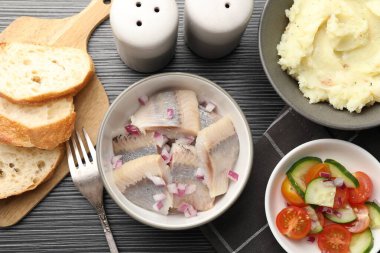 Siyah ahşap masada servis edilen soğanlı lezzetli ringa balıkları.