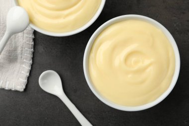 Lezzetli vanilyalı puding ve kaşık siyah masada, düz yatıyordu.