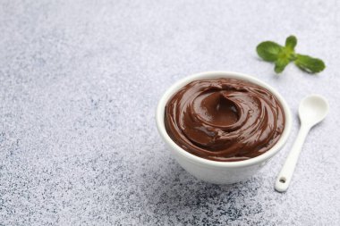 Kasede lezzetli çikolatalı puding ve açık gri desenli masada kaşık. Metin için boşluk