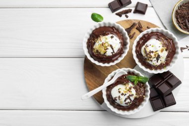 Krem şantili lezzetli puding, beyaz ahşap masa üzerinde çikolata ve kaşık, düz yatak. Metin için boşluk