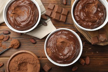 Tabaklardaki lezzetli pudingler, çikolata parçaları ve kakao çekirdekleri ahşap masada, düz yatıyordu.