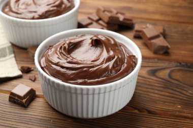 Tabaklardaki lezzetli pudingler ve ahşap masadaki çikolata parçaları, yakın plan.