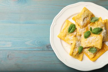 Açık mavi ahşap masada peynirli ve fesleğenli nefis ravioli, üst manzara. Metin için boşluk