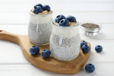 Chia tohumlu lezzetli puding, yoğurt, yaban mersini ve granola beyaz ahşap masada, yakın plan. Süper yemek.