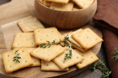 Tahta masanın üzerinde kekik olan lezzetli tuzlu krakerler, yakın plan.