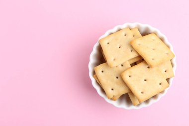 Pembe arka planda leziz tuzlu krakerler, üst manzara. Metin için boşluk