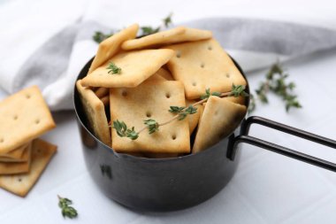 Lezzetli tuzlu krakerler ve kekik beyaz döşemeli masada, yakın plan.