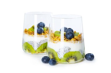 Chia tohumlu lezzetli tatlı, yoğurt, granola, yabanmersini ve kivi beyaz üzerine izole edilmiş bardaklarda. Süper yemek.