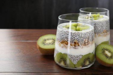 Süper yemek. Chia tohumlu lezzetli tatlı, yoğurt, tahıl gevreği ve ahşap masada kivi, yakın plan. Metin için boşluk