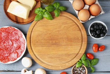 Pizza yapıyorum. Gri ahşap masadaki farklı malzemeler. Metin için boşluk