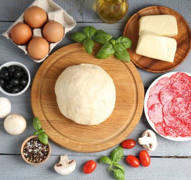 Pizza yapıyorum. Gri ahşap masadaki farklı malzemeler.