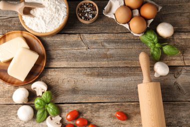 Pizza yapıyorum. Tahta masadaki farklı malzemeler, düz yatış. Metin için boşluk