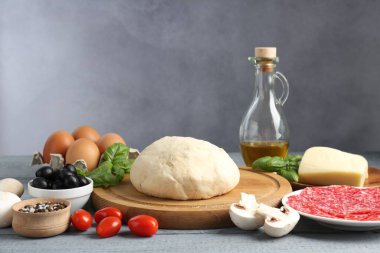 Pizza yapıyorum. Gri ahşap masadaki farklı malzemeler.