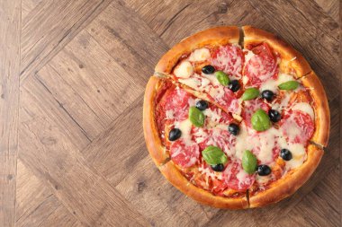 Tahta masada salamlı, peynirli, fesleğenli ve zeytinli lezzetli pizza. Metin için boşluk