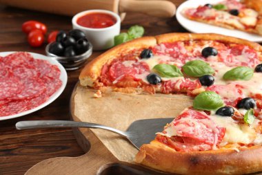 Lezzetli pizza ve malzemeler ahşap masada, yakın plan.