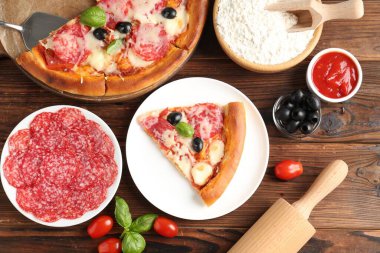 Lezzetli pizza ve malzemeler ahşap masada, düz yatıyordu.