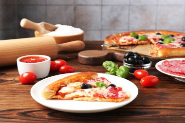 Lezzetli pizza ve malzemeler ahşap masada, yakın plan.