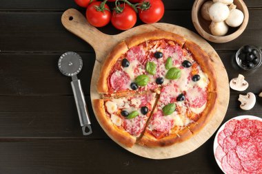 Lezzetli pizza, malzemeler ve siyah ahşap masa, düz yatak. Metin için boşluk