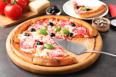 Gri masada lezzetli pizza ve malzemeler, yakın plan.