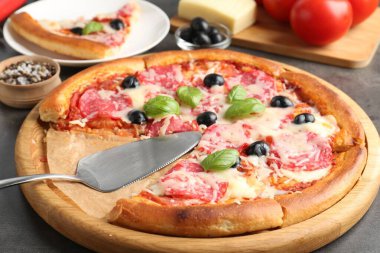 Gri masada lezzetli pizza ve malzemeler, yakın plan.