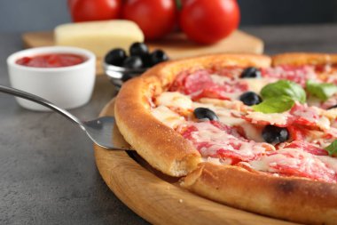 Gri masada servis edilen lezzetli pizza, yakın plan.